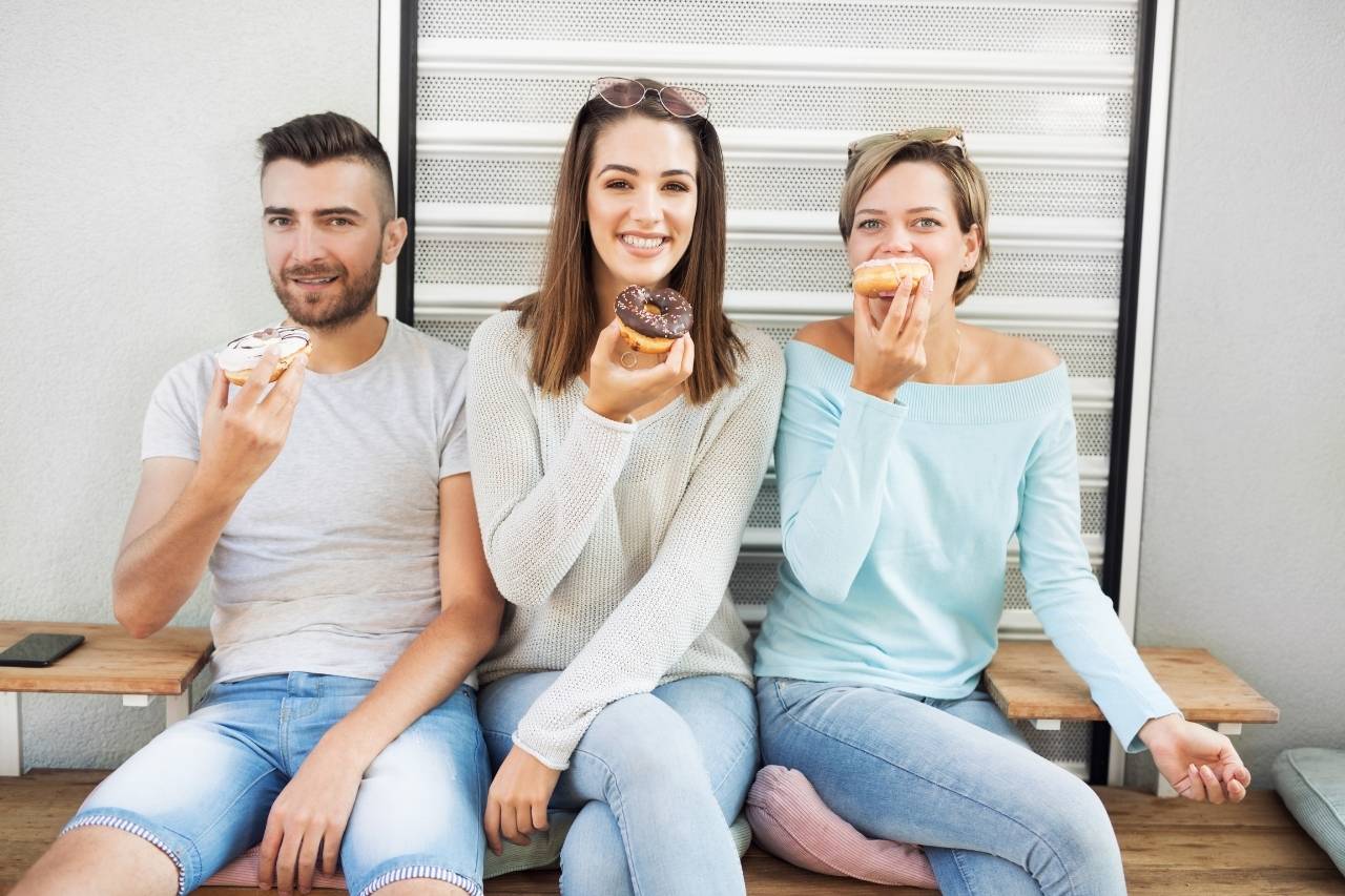 3 friends outside, eating donuts